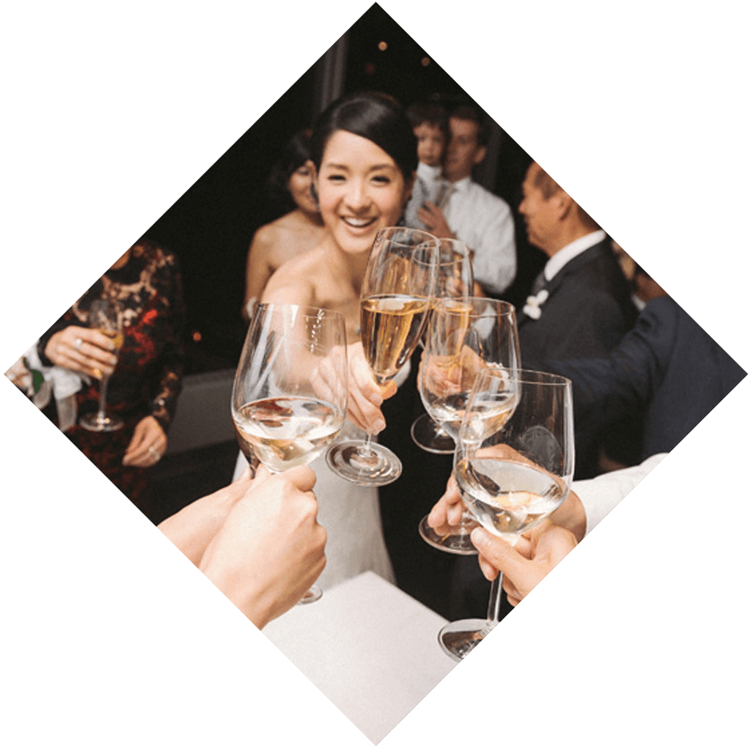 a bride toasting a champagne glass with 4 other champagne glasses while guests watch in the background